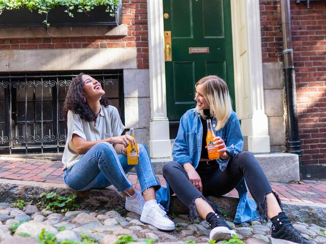 two girls drinking on a pavement